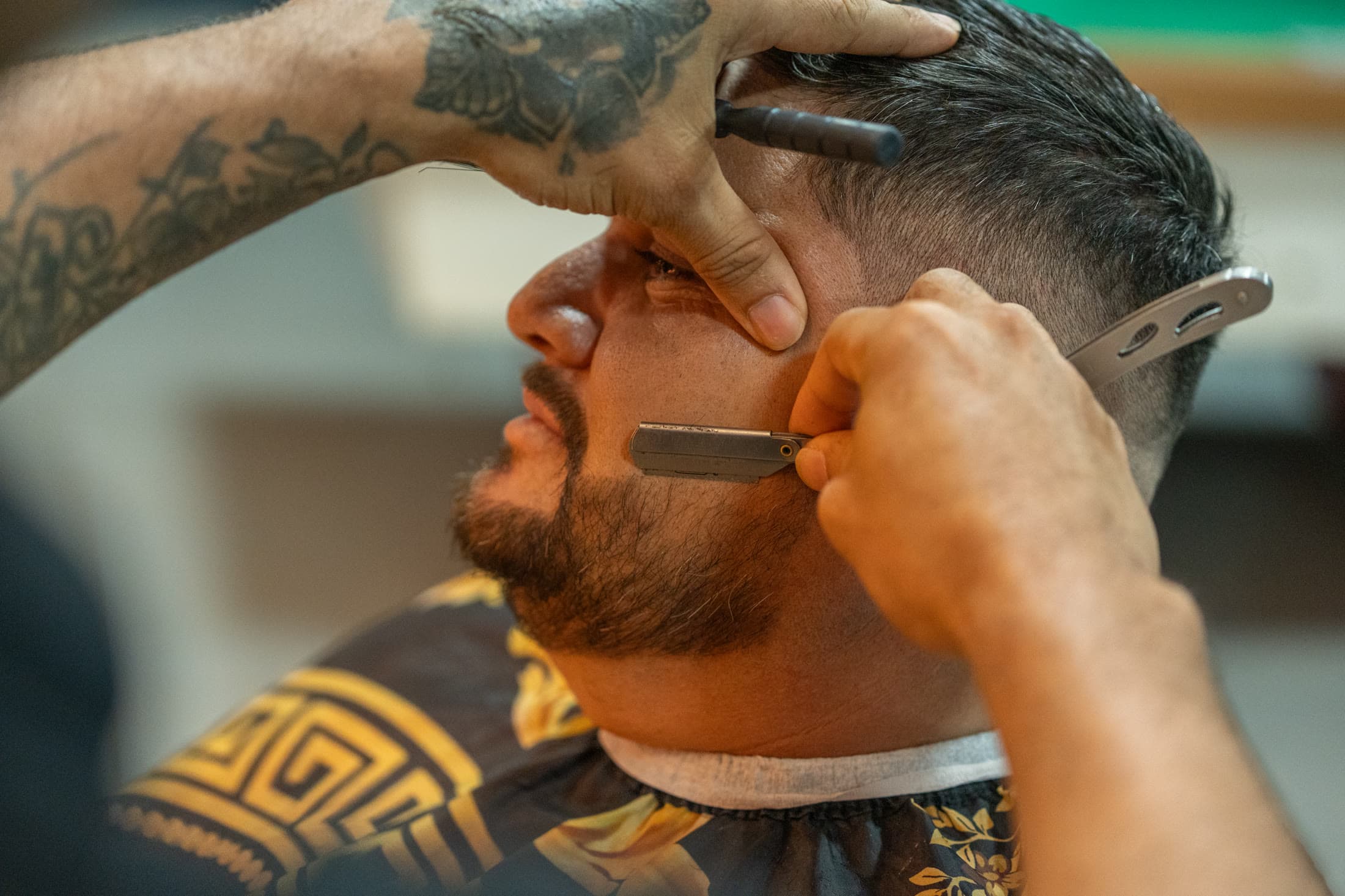 Barbeiro fazendo a barba com navalha